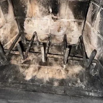Fireplace grate with heavy soot buildup scheduled for cleaning in Kirkland, WA.